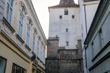 Fototapeta na wymiar Gothic tower of the Velvary Gate, town fortifications built in the pre-Hussite period in sunny day, street of historic medieval city Slany, Central Bohemia, Czech Republic