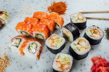 Close up view on assorted Japanese sushi food and rolls on bright table, chopsticks and ingredients
