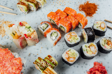 Close up view on assorted Japanese sushi food and rolls on bright table, chopsticks and ingredients
