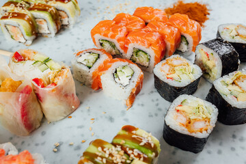 Close up view on assorted Japanese sushi food and rolls on bright table, chopsticks and ingredients