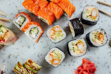 Close up view on assorted Japanese sushi food and rolls on bright table, chopsticks and ingredients