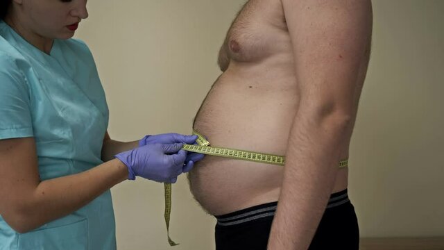 Doctor measures the abdominal circumference of an overweight patient.