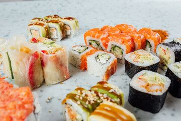 Close up view on assorted Japanese sushi food and rolls on bright table, chopsticks and ingredients