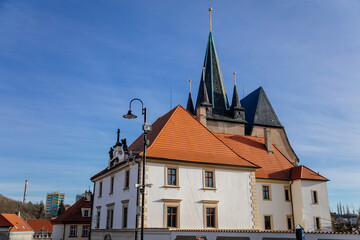 Narrow picturesque street with colorful buildings in historic center in medieval city Slany, renaissance houses and gothic church of Saint Gothard, Central Bohemia, Czech Republic