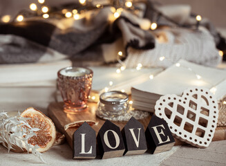 Cozy home composition with decorative word love on blurred background with bokeh.