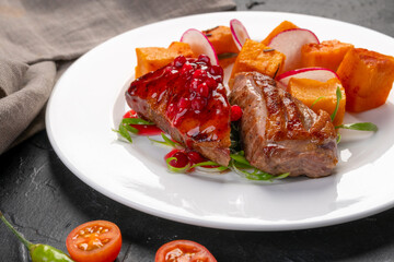 grilled farm duck breast with baked sweet potatoes and sweet lingonberry sauce. Tareka white on a dark background. For the restaurant menu.