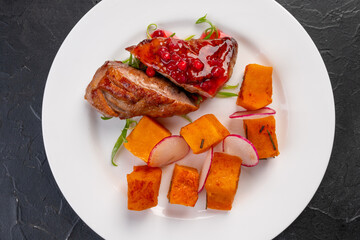 grilled farm duck breast with baked sweet potatoes and sweet lingonberry sauce. Tareka white on a dark background. For the restaurant menu.