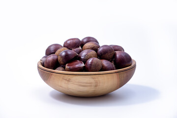 Chestnuts in a wooden bowl on white background. Castanea sativa, sweet ripe Chestnuts