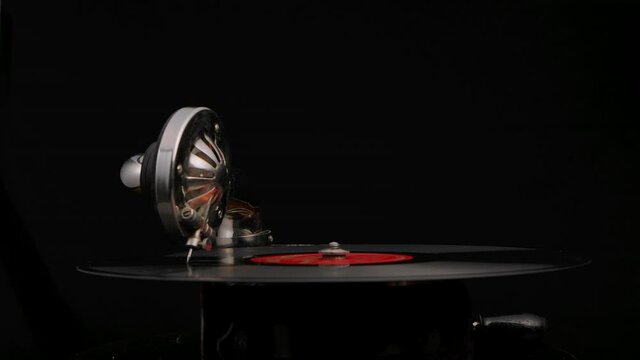 Vintage old record player gramophone needle on vinyl record. Wooden case turntable rotates on black studio background. Retro style part close up. Slow motion.