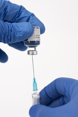 Close up human fingers in gloves, holding covid-19 vaccine vial and syringe with needle. Medical concept.