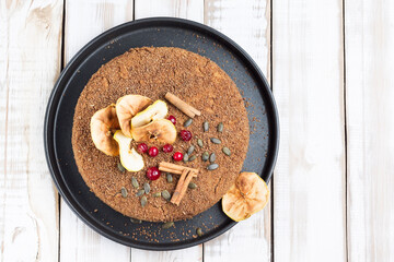 Gluten-free nut cake with creamy Apple filling on a black tray on a light wooden background.
