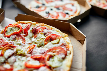Open box with hot tasty italian sliced pizza on black background