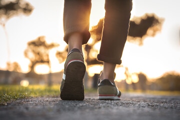 Woman walking outdoors on sunset. Closeup on shoe with rolled up jeans. Taking a step. New life...