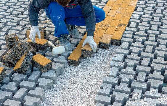 Paving stone worker is putting down pavers during a construction of a city street.