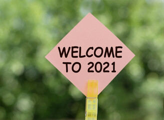 WELCOME TO 2021. Text on pink note paper on green background.