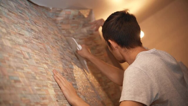 Happy young family doing renovations in their new apartment, gluing wallpaper