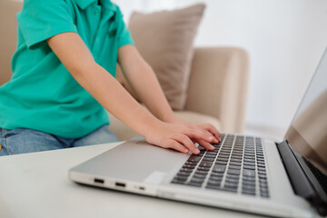 Cropped image of boy typing on laptop when studying at home due to coronavirus pandemic