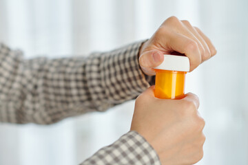 Close-up image of patient opening plastic bottle of tablets he is taking every day