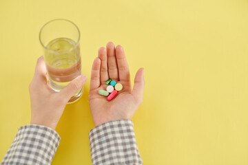 Hands of patient taking various supplements, vitamins and glass of water
