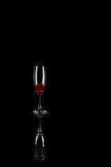 Glass cup with drink inside on top of another empty glass on black background