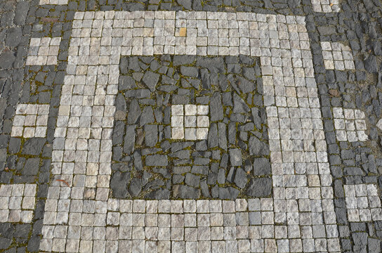 mosaic of small marble cubes. sidewalks and squares formed by stone carpet with squares, polka dots waves pattern. stone carpet pink, white dark background. basalt rough paving in the space under the 