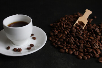 cup of coffee and coffee beans in a sack on dark background, top view.