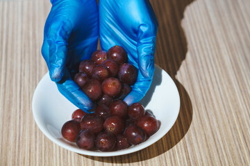 hands in gloves holding grape on plate