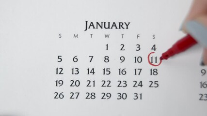 Female hand circle day in calendar date with a red marker. Business Basics Wall Calendar Planner and Organizer. JANUARY 11th