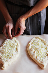 Obraz na płótnie Canvas Household. Women's hands form dough sprinkled with cheese for making khachapuri. Family celebration.