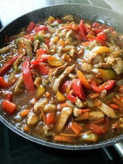 delicious homemade lunch - meat with vegetables in a sweet sauce cooked in a large frying pan