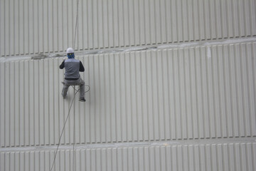 working man on the high building . Building maintenance cleaning and paint the exterior of the building wall. 