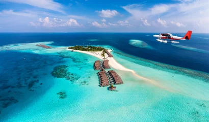  Een watervliegtuig nadert een tropisch paradijselijk eiland op de Malediven met een turquoise zee en zonneschijn © moofushi