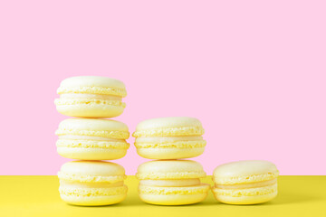 Five yellow lemon macarons on a yellow and pink background in the form of a pyramid. Valentine's day gift dessert