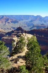Grand Canyon in Arizona, South Rim, multicolored rock layers, a man on the rock in the middle is taking photos, a sunny day in September