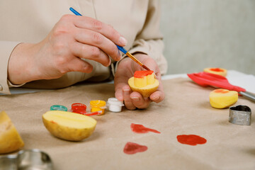 heart shaped potato stamp on craft paper. The process of decorating a gift for Valentine's Day. Getting ready for the celebration on February 14th.