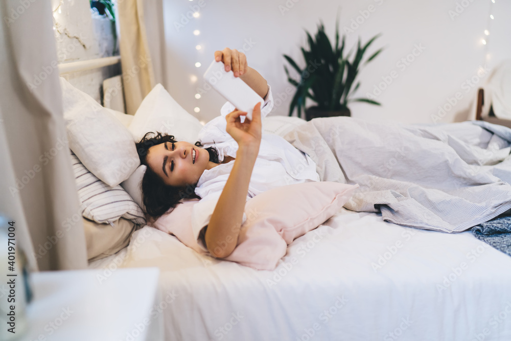Aufkleber beautiful woman checking network news after awaking using smartphone gadget and home internet connec