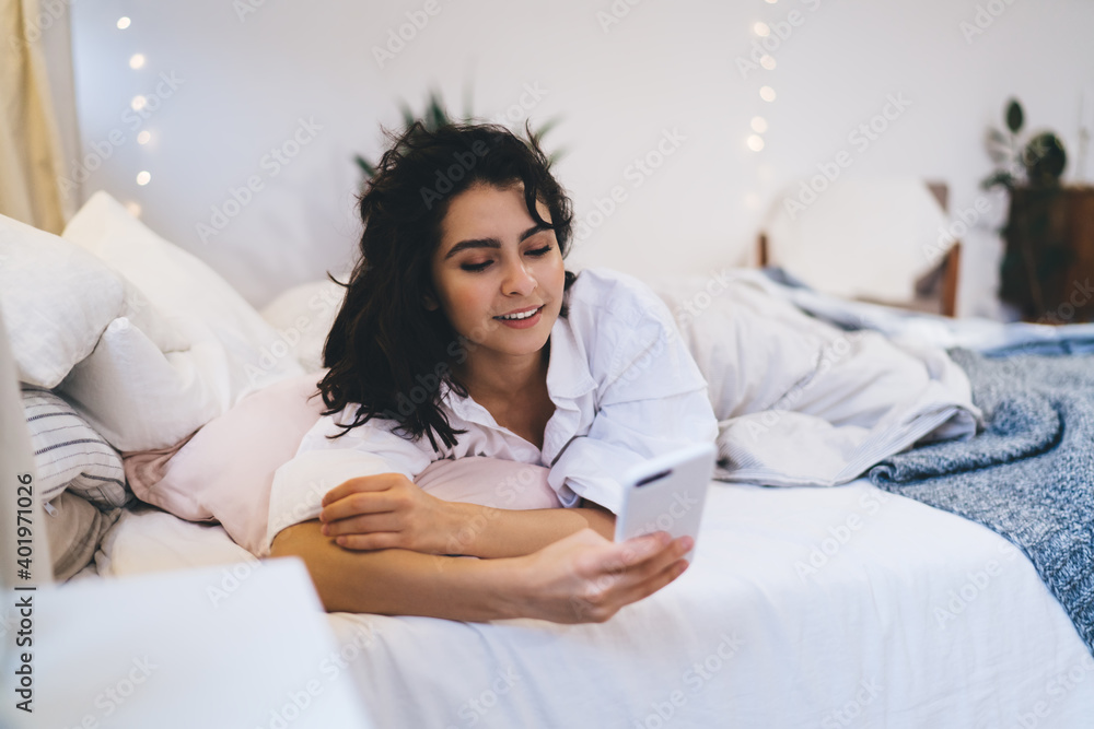 Aufkleber beautiful woman checking network news after awaking using smartphone gadget and home internet connec