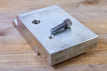 Screw thread in a steel billet on a wooden board. Hex head bolt.