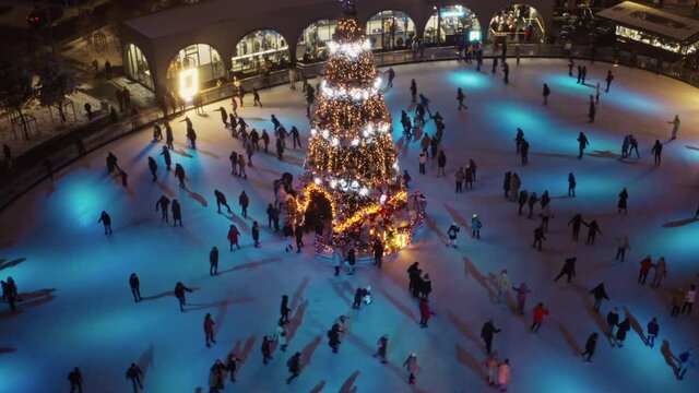 New Year's lighting in the city square. You can see the ice rink, buildings and city streets. Aerial view. Christmas Ice Skating. Amazing huge Christmas tree, ice rink and decorated building at night