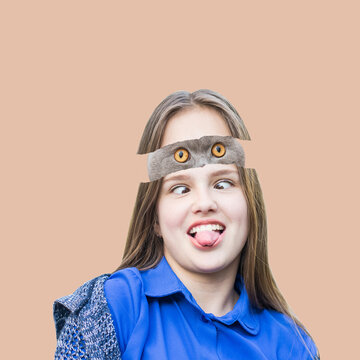 Cute teenage girl with funny cat in her head showing tonque on pink background. Art collage with allien cat. Free space for text.