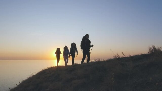 The four travelers walking on the mountain top near the sea. slow motion