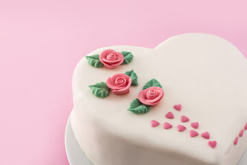 Heart cake for St. Valentine's Day, Mother's Day, or Birthday, decorated with roses and pink sugar hearts on pink background	