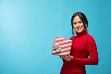 Portrait of young woman wearing red sweatshirt and holding gift box in hand	