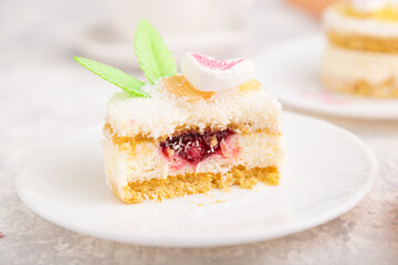 Decorated cake with milk and coconut cream with cup of coffee on a gray concrete background. Side view, selective focus.