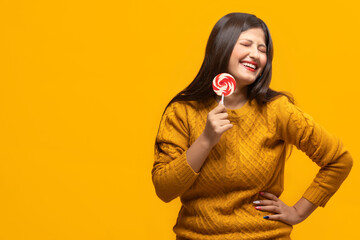 Young woman laughing holding a lollipop in hand	