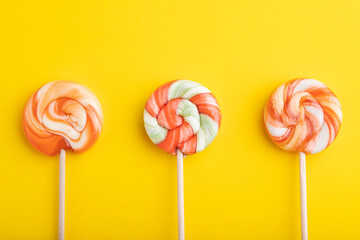 Three lollipop candies on yellow background. copy space, top view