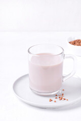 Buckwheat milk in the glass mug on the white table. Vegan milk without lactose