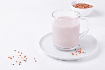Buckwheat milk in the glass mug on the white table. Vegan milk without lactose