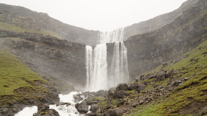 Green mountain landscapes with a wild waterfall near Gjogv village on the Faroe Islands in Denmark.