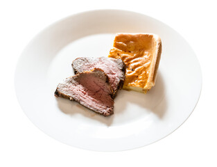 home-made sliced Roast Beef and piece of Yorkshire pudding on white plate cut out on white background